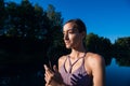 Young female practicing yoga against the sky on a sunrise. Pretty slim woman performs an exercise. Healthcare, meditaion