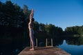 Young female practicing yoga against the sky on a sunrise. Pretty slim woman performs an exercise. Healthcare, meditaion