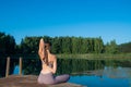 Young female practicing yoga against the sky on a sunrise. Pretty slim woman performs an exercise. Healthcare, meditaion