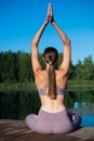 Young female practicing yoga against the sky on a sunrise. Pretty slim woman performs an exercise. Healthcare, meditaion