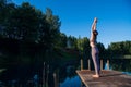 Young female practicing yoga against the sky on a sunrise. Pretty slim woman performs an exercise. Healthcare, meditaion