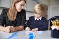 Young female primary school teacher and schoolboy sitting at a table working one on one, looking down, front view, close up Royalty Free Stock Photo