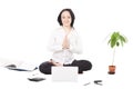 Young female professional resting in lotus pose in front of laptop on white background