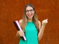 Young female professor or business woman holds folders and doing winnng gesture outdoor