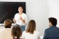 Young female professor explaining subject to classroom full of students Royalty Free Stock Photo