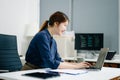 Young female programmer working with tablet and screen displaying code. Modern tech office setup, great for software, coding, IT Royalty Free Stock Photo