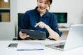 Young female programmer working with tablet and screen displaying code. Modern tech office setup, great for software, coding, IT Royalty Free Stock Photo