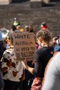 Young female protestor holding a `White Australia we need to do better` placard