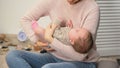 Young female putting cute newborn baby girl to sleep, infant colic relieving