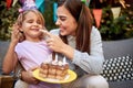 Young female putting whipped cream from a birthday cake on a nose of a cute little girl Royalty Free Stock Photo