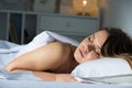 Young female in pygamas is sleeping on bed