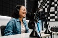 Young female radio host using microphone and headphones in studio Royalty Free Stock Photo