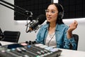 Young female radio host using microphone and headphones in studio Royalty Free Stock Photo