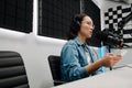 Young female radio host using microphone and headphones in studio Royalty Free Stock Photo