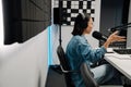 Young female radio host using microphone and headphones in studio Royalty Free Stock Photo