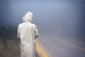 Young female in a raincoat on the road in the fog. Travel of women in the raincoat hitchhiking in the rain Royalty Free Stock Photo