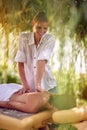 Female receiving back massage from a massage professional at beauty salon in nature.
