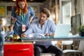 Young female redhead employee explaining data in a document to a middle aged beardy boss, who is analyzing report