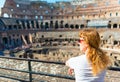 Young female redhead tourist looks at the Colosseum in Rome