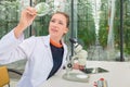 Young female researcher examining leaves under microscope at lab