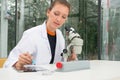 Young female researcher using microscope and digital tablet at t