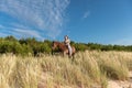 Young female rider atop a beautiful horse, cantering through a meadow of lush grass