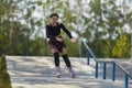 Young female riding on inline skates in a concrete skatepark in summer. Cool tattooed person skating outdoor in the morning