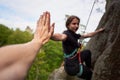 Rock climber climbing overhanging rock with rope. Man helping woman rock climbing. Holding hands.