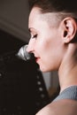 young female rock singer with microphone, smiling and singing. rear view. close up. woman with short hair singing on a Royalty Free Stock Photo