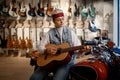 Young female rocker playing guitar at music shop sitting on motorcycle Royalty Free Stock Photo