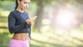 Young female runner listening to motivational music on smartphone app