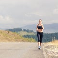 Young female runner on road cross in mountains Royalty Free Stock Photo