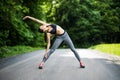 Young female runner stretching arms before running. Woman warming before workout in the park