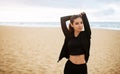 Young female runner stretching hands at the beach, warming up and smiling at camera, exercising by seaside, free space Royalty Free Stock Photo