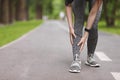 Young female runner suffering from shin splints while jogging in park Royalty Free Stock Photo