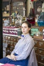 Young female sales assistant sitting down in Victorian Chemist/ Royalty Free Stock Photo