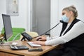 Young female sales Manager in a face mask talking on the phone in the office Royalty Free Stock Photo