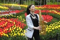 Young female saxophonist playing saxophone on a bright tulips lawn background