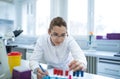 Young female scientist holding vial taking notes in lab