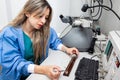 Young female scientist loading a grid with an specimen on the sample holder of a transmission electron microscope