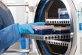 Young female scientist sterilizing laboratory material in autoclave Royalty Free Stock Photo