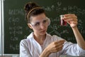 female scientist in white coat and glasses holding laboratory flask with red liquid