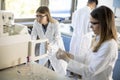 Female scientists in a white lab coat putting vial with a sample for an analysis on a ionchromatography system in biomedical lab