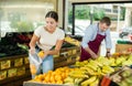 Young female shopper selects and buys fresh oranges in supermarket Royalty Free Stock Photo