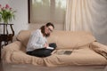 Young female sitting on the couch in the living room and working remotely at home Royalty Free Stock Photo