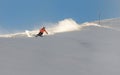 A young female skier in an orange jacket turns carving arches on the slope. A beautiful sunny day in the mountains, on the ski Royalty Free Stock Photo