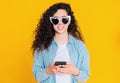 Young female smiling and using mobile phone over yellow background. Beautiful mixed race girl holding and texting with Royalty Free Stock Photo