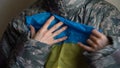 Young female soldier is holding ukrainian flag with love and anxiety due to escalation military conflict on the western