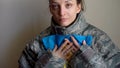 Young female soldier is holding ukrainian flag with love and anxiety due to escalation military conflict on the western