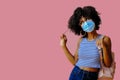 young female student with backpack wearing protective mask and posing on pink background, back to school concept Royalty Free Stock Photo